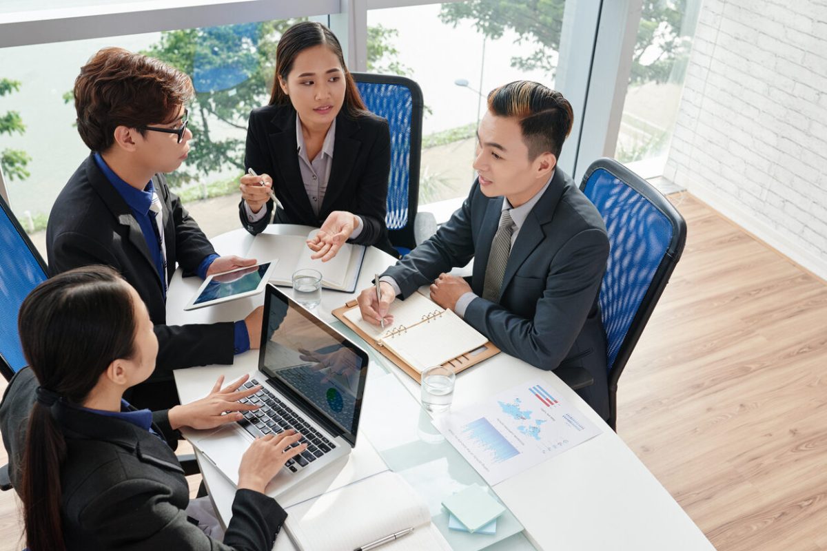 Ambitious group of business people brainstorming on project while having working meeting in modern boardroom, high angle view