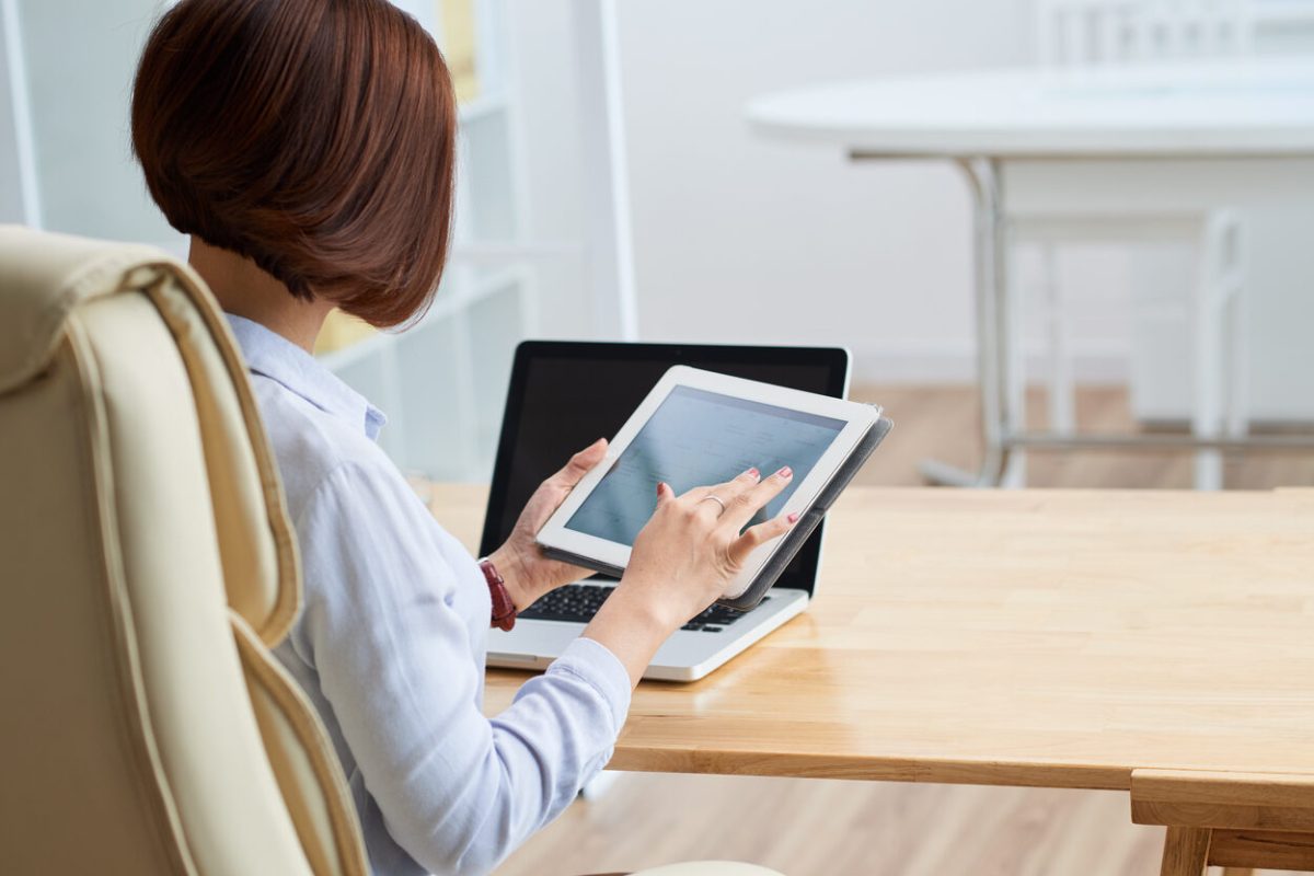 Business woman checking calendar in her digital tablet, view from the back