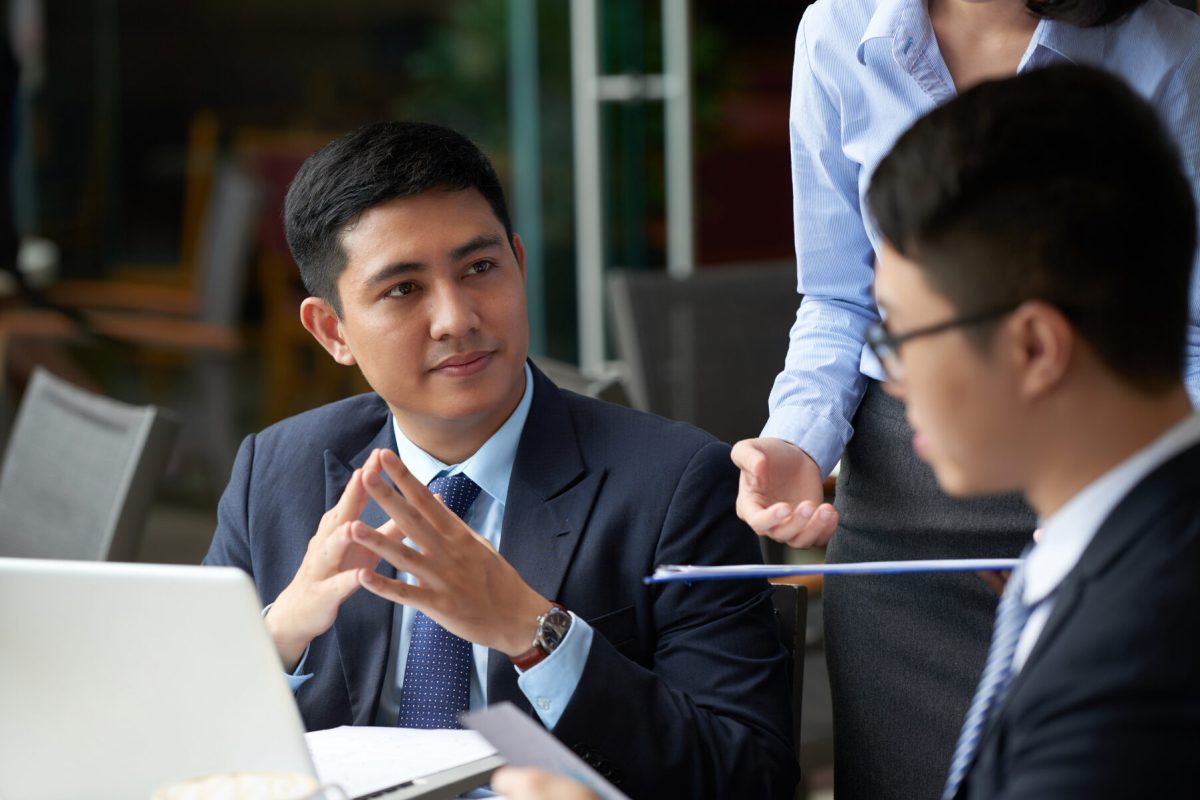 Handsome young businessman having meeting with partners in cafe