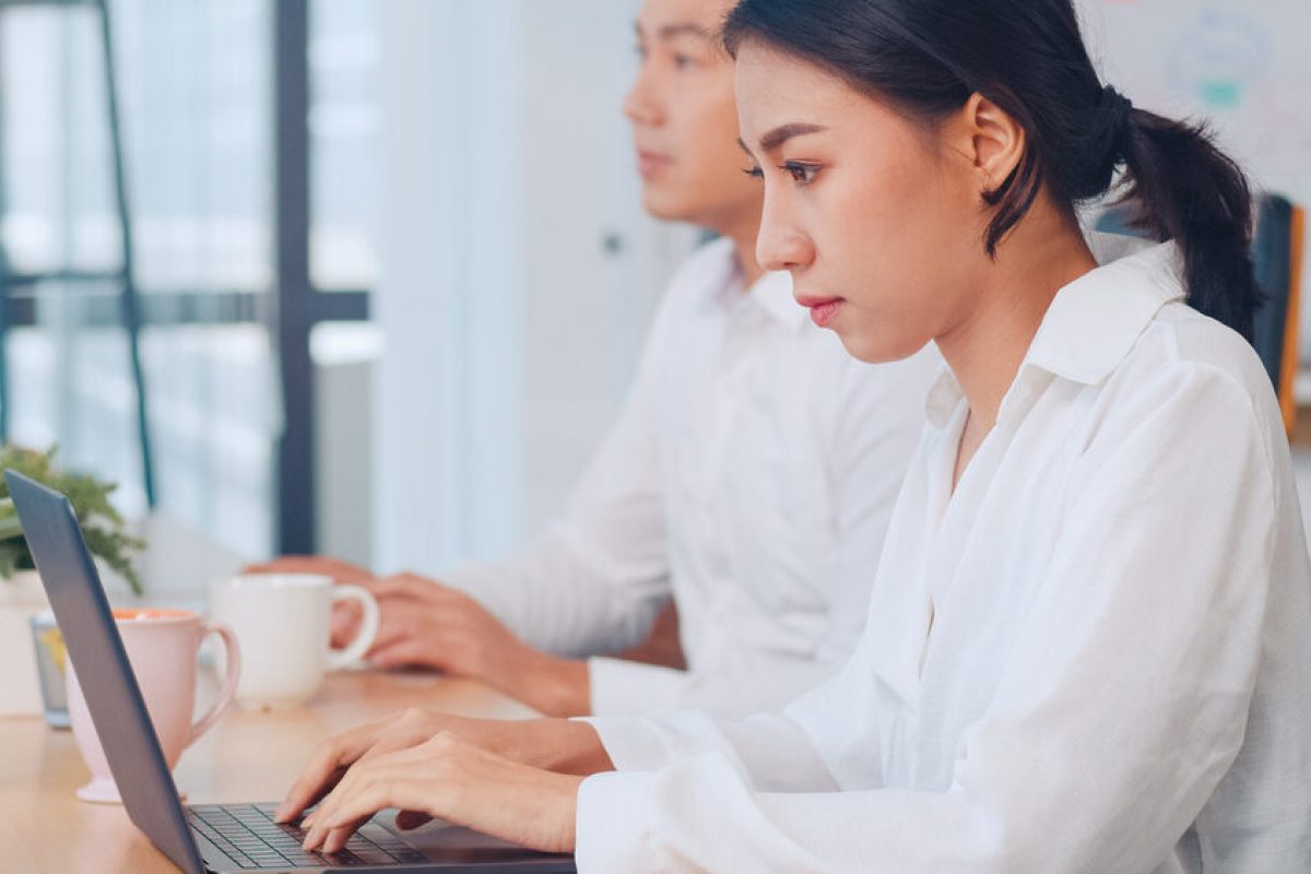 Successful beautiful executive Asia young businesswoman smart casual wear watching tutorial about creative ideas at laptop computer during working process in modern office workplace.